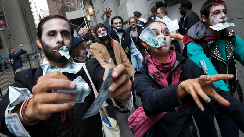 Continua la protesta degli indignados americani con il movimento che inscena una sfilata particolare a Wall Street: tutti travestiti da zombies masticano il denaro del monopolio.