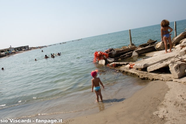 Bagnanti tra le case abusive sommerse dal mare a Bagnara