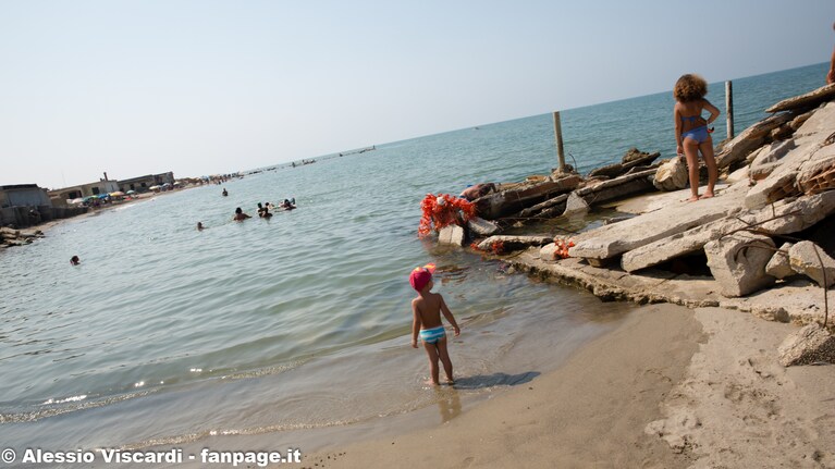 Bagnanti tra le case abusive sommerse dal mare a Bagnara