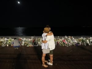 Una coppia si abbraccia sulla Promenade des Anglais davanti a centinaia di mazzi di fiori in ricordo delle vittime dell’attentato (Foto: Getty Images)