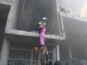 Una bimba mentre viene salvata dalla sua casa ridotta in macerie dopo i bombardamenti (White Helmets).