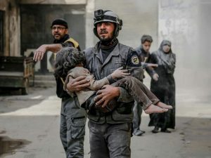 Un volontario dei Caschi bianchi porta in salvo una bambina ferita nei raid sulla Ghouta orientale