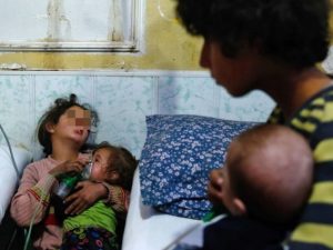 Una bambina tiene la maschera di ossigeno ad una neonata dopo un attacco con gas cloro in Siria (Gettyimages)