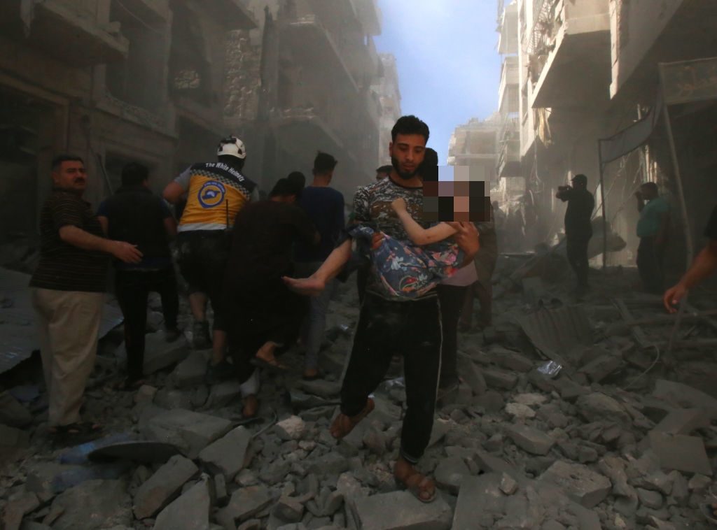Un uomo soccorre una bimba dopo il bombardamento a Maarrat al–Numan (Gettyimages)