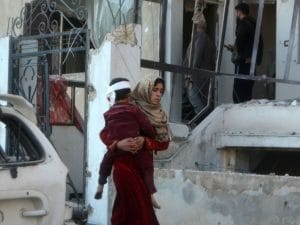 Una donna cerca di mettere in salvo il figlio dopo il bombardamento a Maarrat Misrin (Gettyimages)