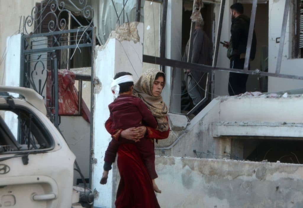 Una donna cerca di mettere in salvo il figlio dopo il bombardamento a Maarrat Misrin (Gettyimages)