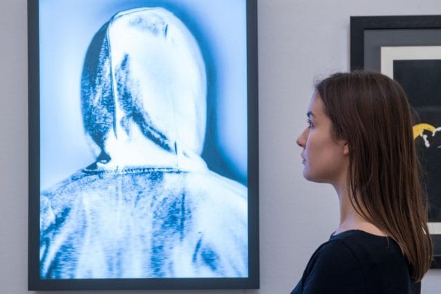 Un dipendente di Sotheby’s posa per le fotografie accanto a ’Banksy’ di Chris Leveine durante un’anteprima della collezione ’Made In Britain’ da Sotheby’s il 15 marzo 2018 a Londra, Inghilterra.