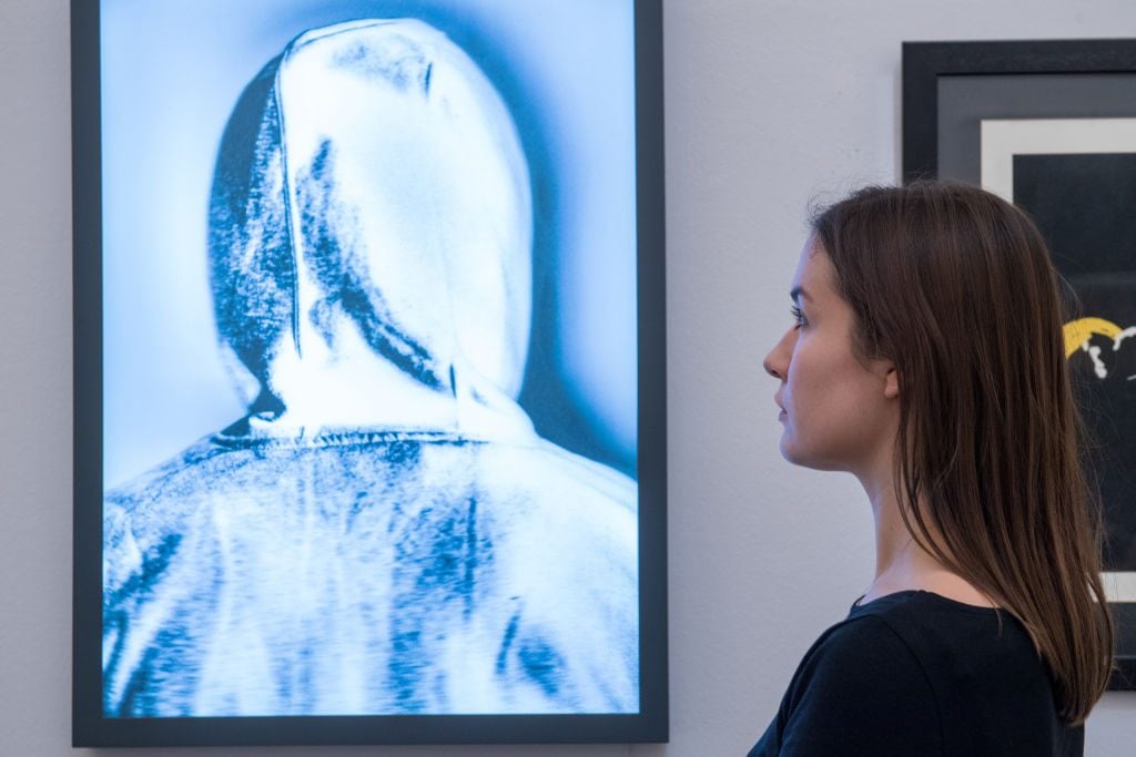 Un dipendente di Sotheby’s posa per le fotografie accanto a ’Banksy’ di Chris Leveine durante un’anteprima della collezione ’Made In Britain’ da Sotheby’s il 15 marzo 2018 a Londra, Inghilterra.