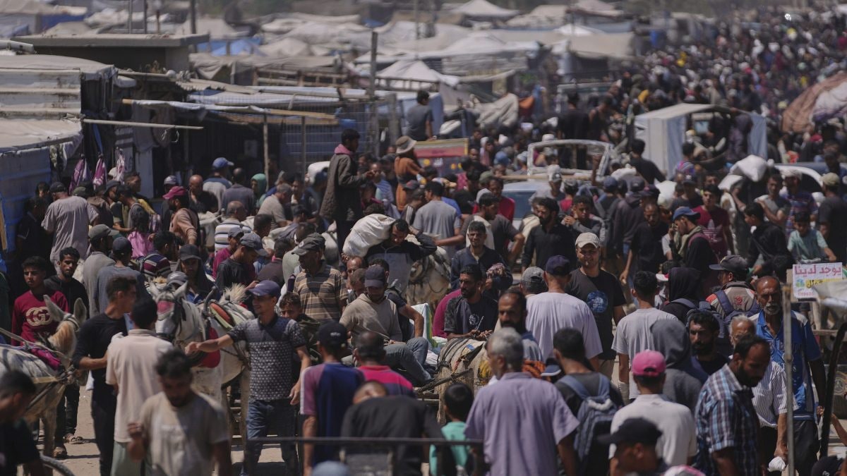 La popolazione palestinese trasporta pacchi di aiuti umanitari consegnati dalla Gaza Humanitarian Foundation, (organizzazione sostenuta dagli Stati Uniti) a Rafah, nella Striscia di Gaza meridionale. (Credit: AP Photo/Abdel Kareem Hana)
