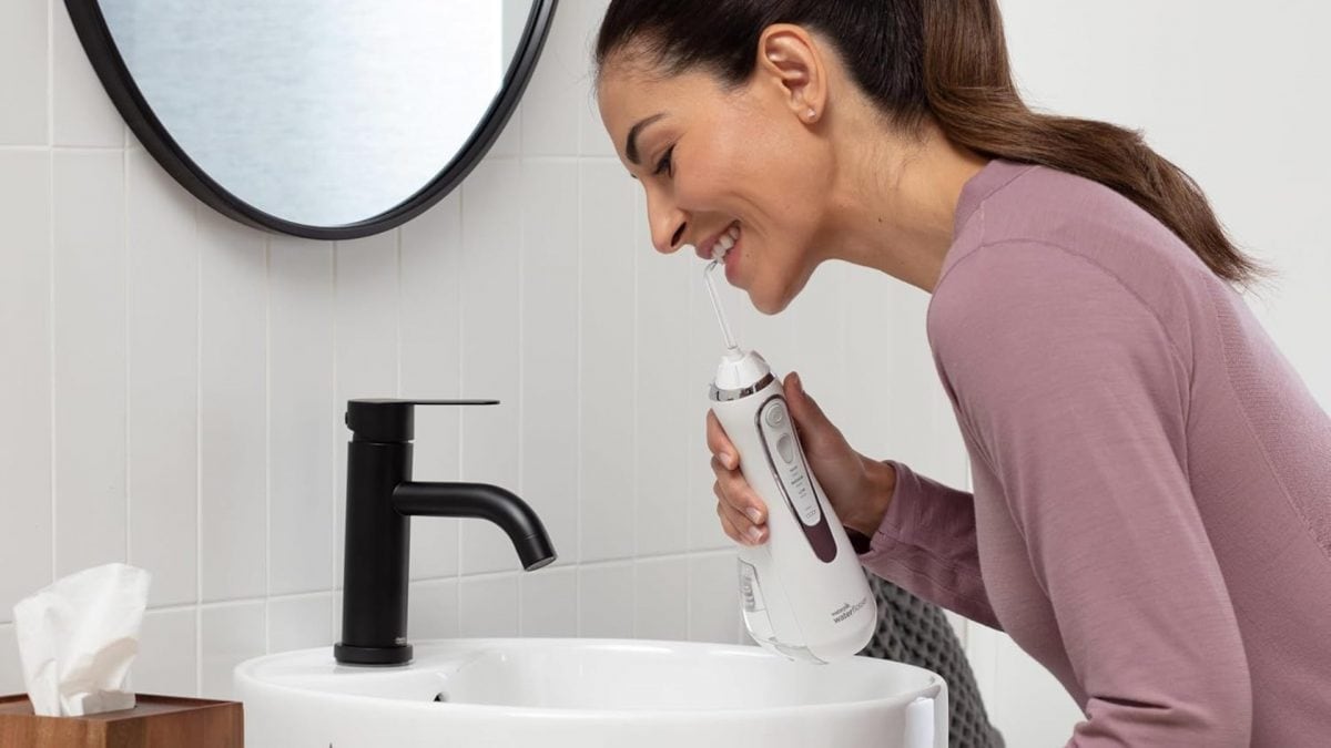Una donna usa l'idropulsore dentale Waterpik per lavarsi i denti