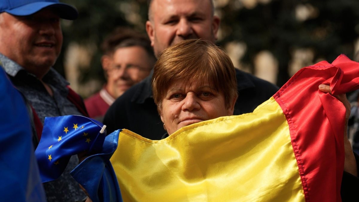 Una donna strisce la bandiera della Moldavia e quella dell’Ue.