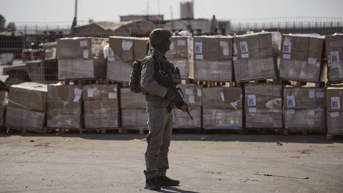 Un soldato israeliano accanto ai pacchi di aiuti umanitari al valico di Kerem Shalom nella Striscia di Gaza