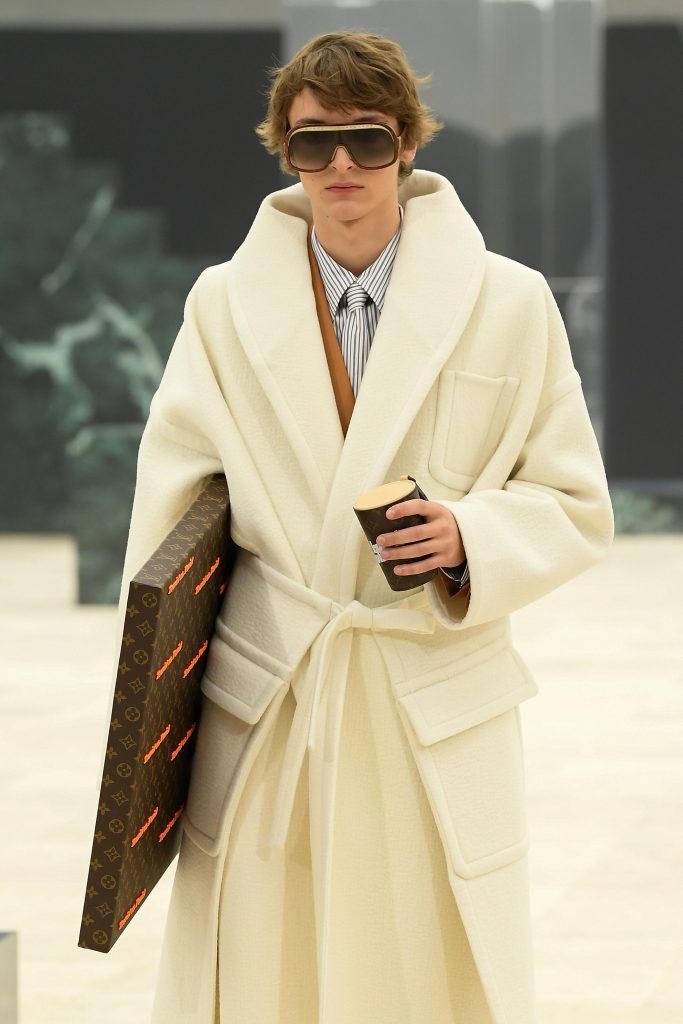 Un modello sulla passerella di Louis Vuitton con un cappotto a vestaglia bianco panna