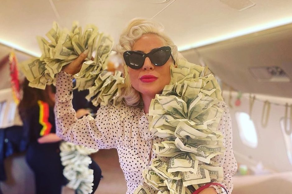 Lady Gaga come una diva sul jet privato: boa di banconote e borsa firmata da oltre 20mila euro