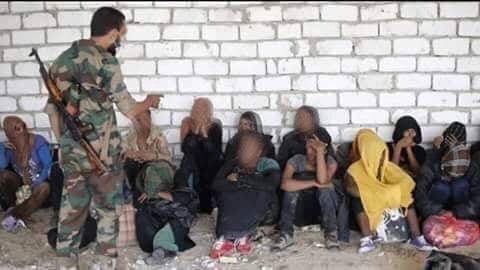 Un militare libico si rivolge minaccioso verso un gruppo di detenuti nel centro di Kesher bin al Kesher, a sud di Tripoli