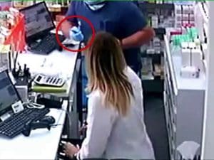 Il rapinatore mentre minaccia il personale con un taglierino