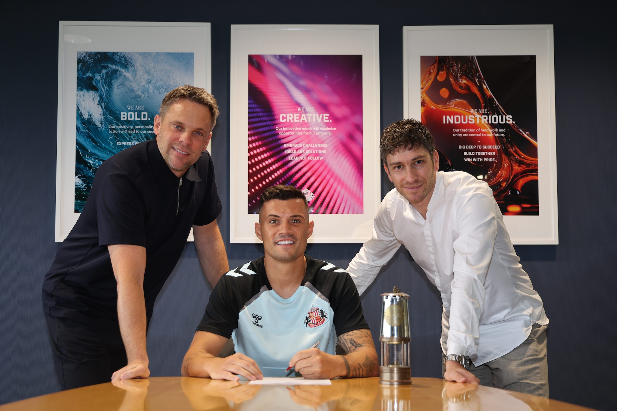 Xhaka durante la firma col Sunderland insieme all’ex Roma, Ghisolfi.