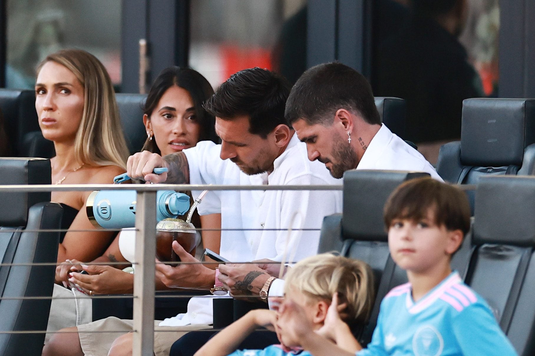 Messi mentre mostra il suo orologio durante la partita in compagnia di De Paul e di sua moglie.