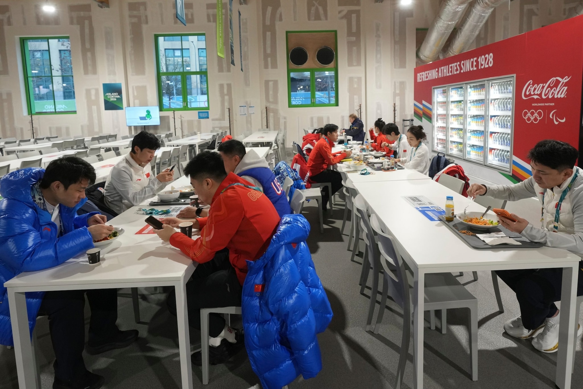 Alcuni atleti mangiano alla mensa del Villaggio Olimpico milanese