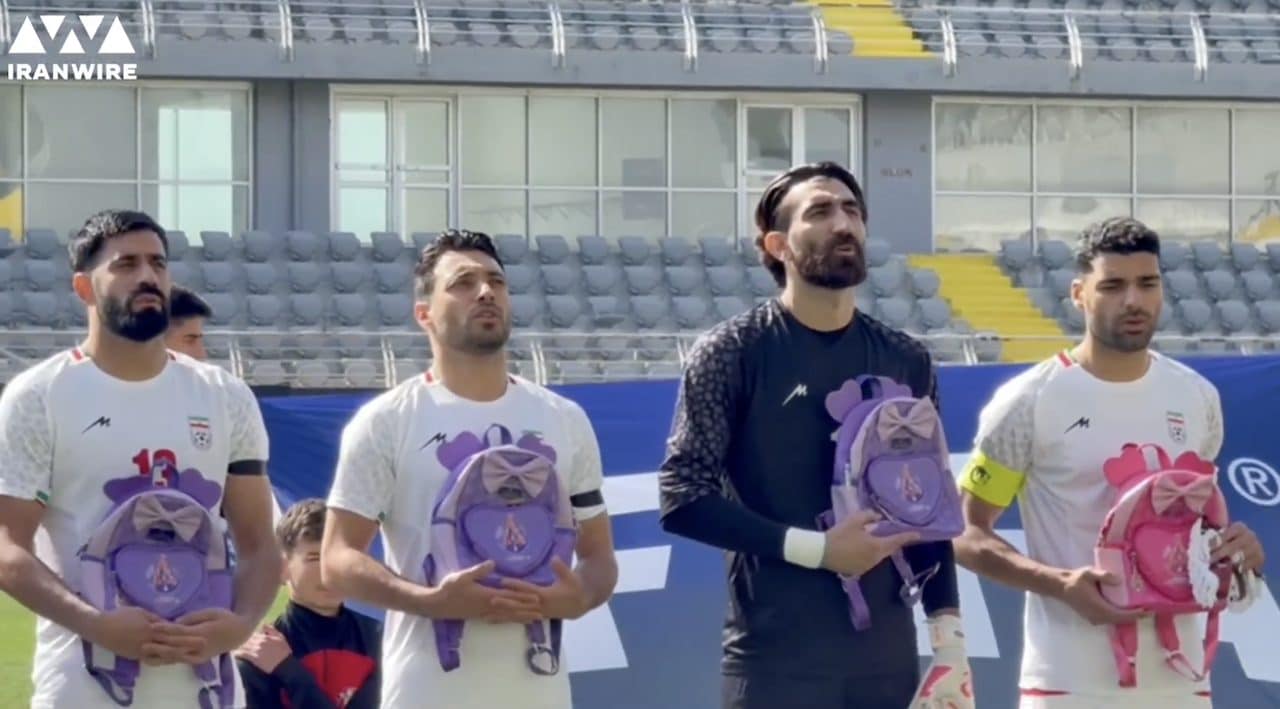 I calciatori dell'Iran con uno zainetto colorato durante l'inno nazionale in segno di protesta