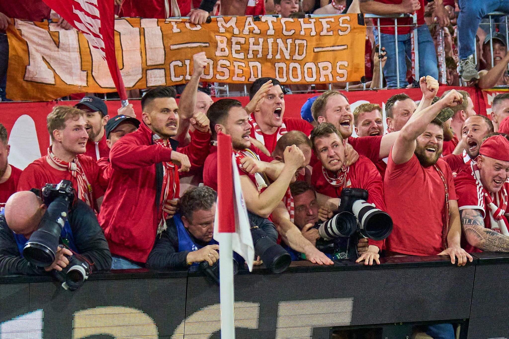 I fotografi schiacciati dai tifosi del Bayern dopo il gol del 4–3 di Olise: di lì a poco saranno travolti