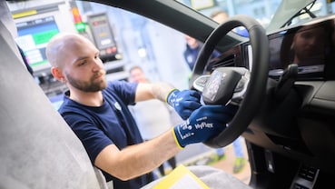 Operatore con guanti blu al lavoro sul volante di un’auto, accanto al modulo centrale dell’airbag.