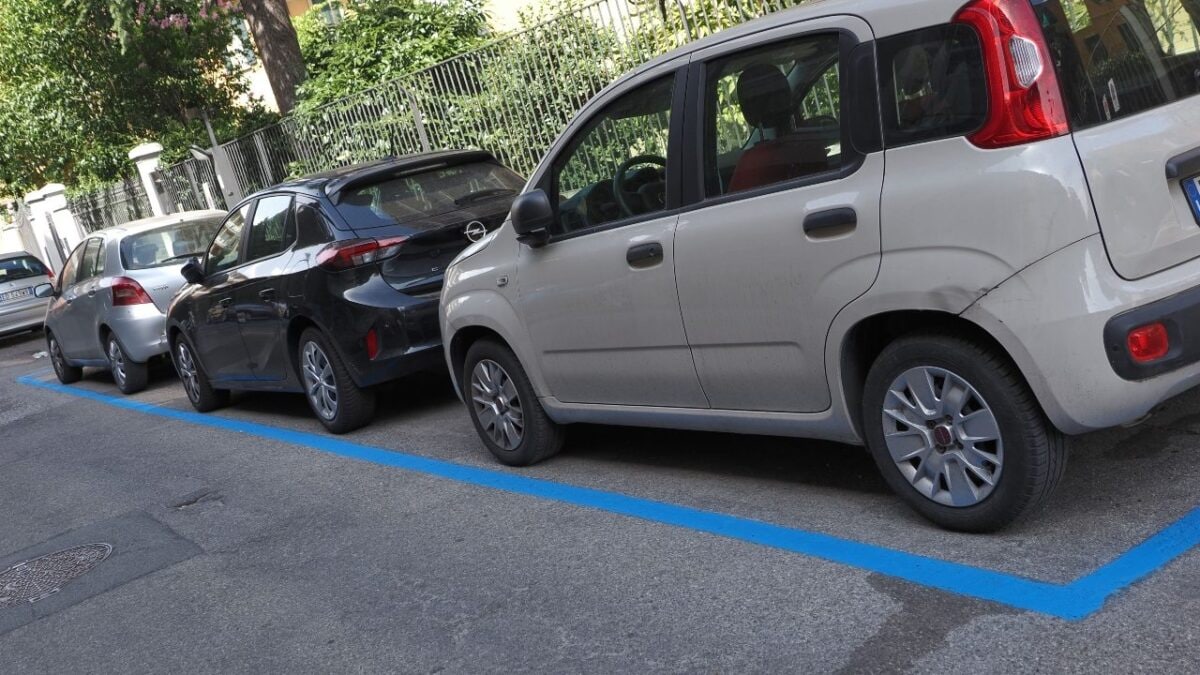 Auto parcheggiate negli stalli delimitati dalle strisce blu, con una Fiat Panda bianca in primo piano.