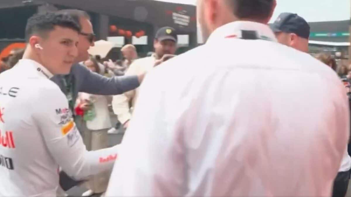 Isack Hadjar tende il braccio verso un uomo nel paddock del GP del Messico di Formula 1, mentre altre persone assistono alla scena.