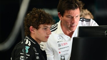 Kimi Antonelli e Toto Wolff osservano insieme un monitor nel box Mercedes di Formula 1.