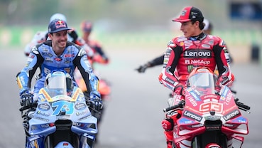 Alex Marquez e Marc Marquez si guardano sorridendo mentre sono sulle rispettive Ducati nel paddock della MotoGP.