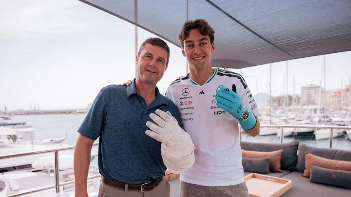 Reid Wiseman e George Russell sorridono insieme, mostrando rispettivamente un guanto da astronauta e uno da pilota Mercedes di Formula 1.