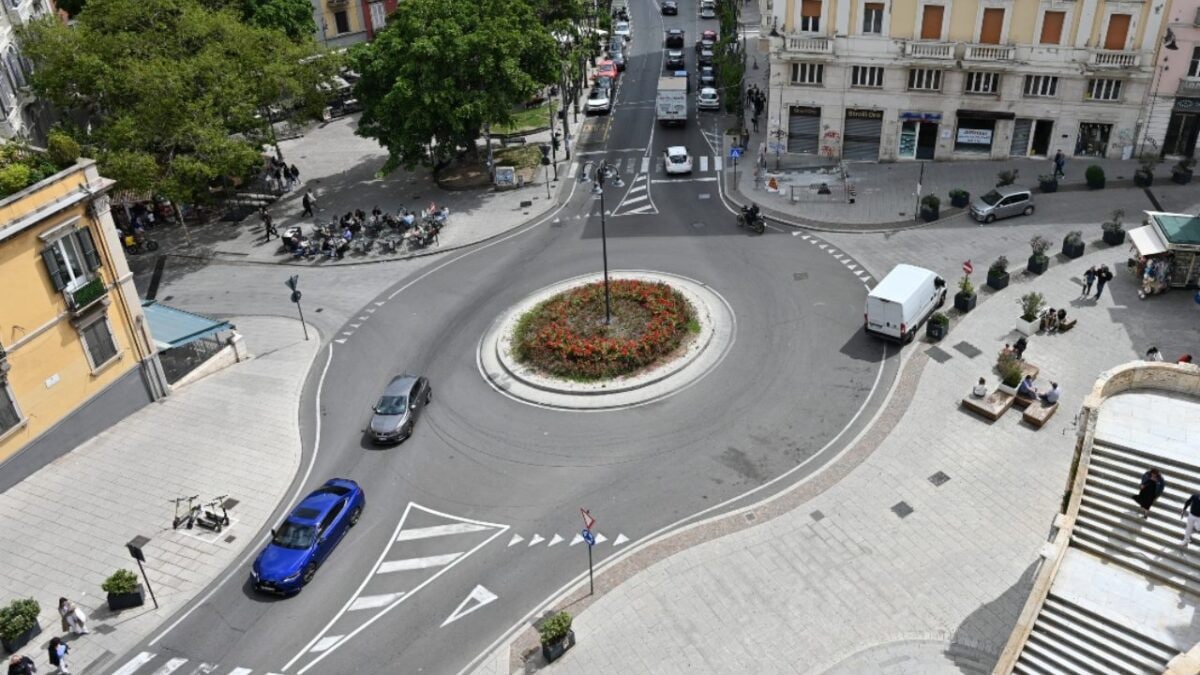 Rotatoria urbana vista dall'alto, con auto in transito e segnaletica di dare precedenza agli ingressi.
