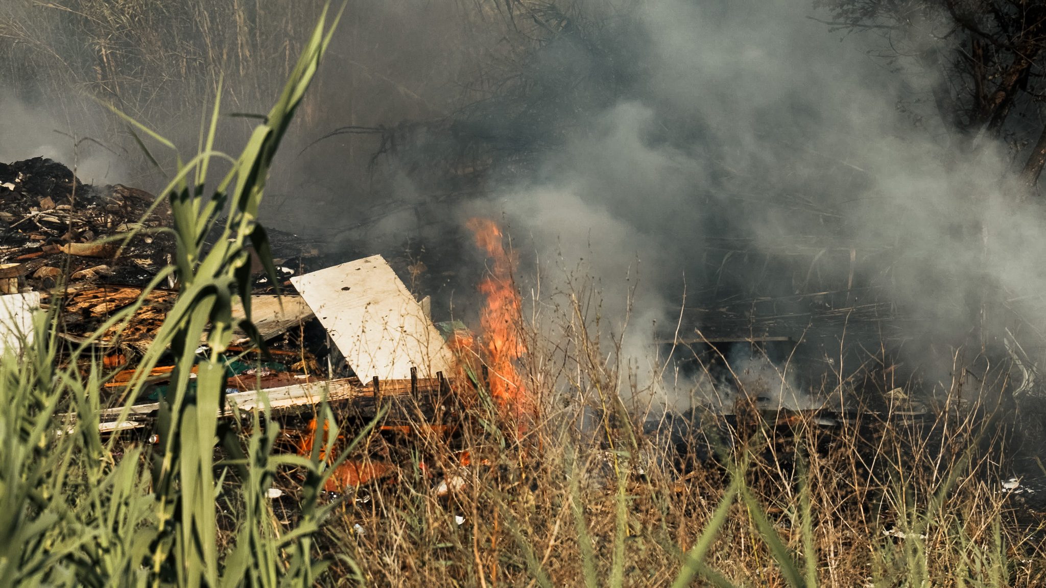I cumuli di rifiuti a fuoco sulla sponda del Tevere, foto di Gabriel Bernard.