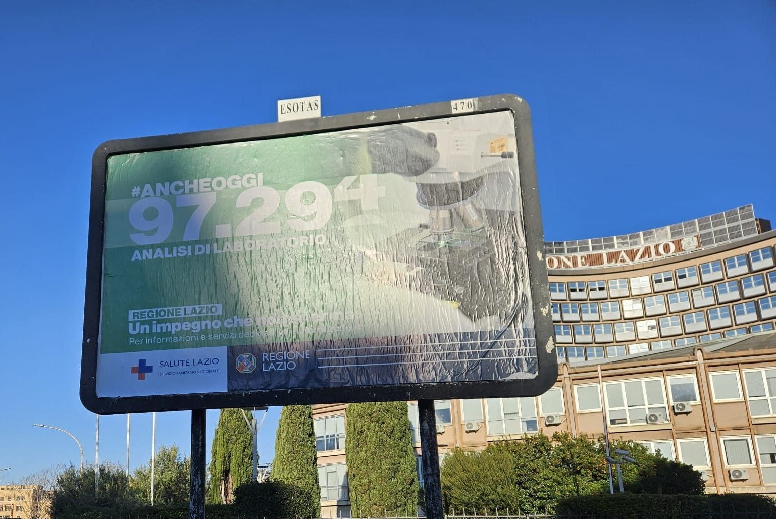 Uno dei manifesti della campagna "Anche oggi" davanti alla sede della Regione Lazio a Roma