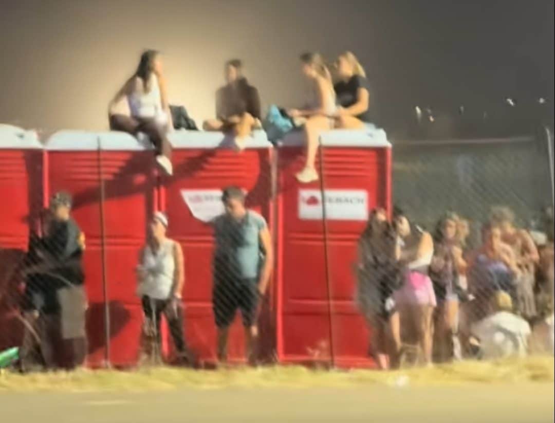 Persone arrampicate sui bagni chimici per cercare di vedere il concerto di Ultimo a Tor Vergata. Da un video TikTok.