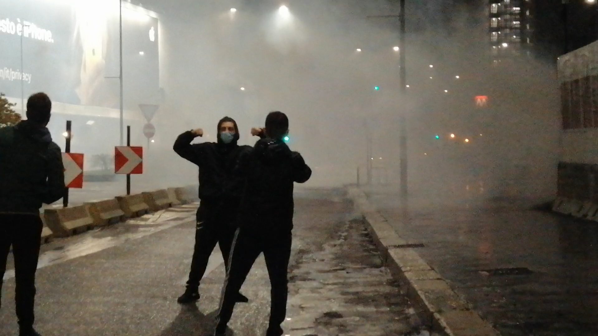 Durante la violenta protesta a Milano, mentre la polizia lanciava i lacrimogeni, un contestatore si è messo in posa per una foto