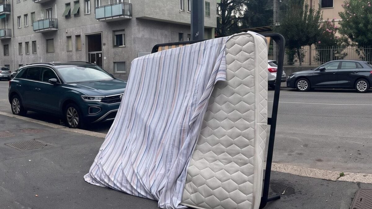 Letto matrimoniale abbandonato con materasso e lenzuola in Largo Vulci a Milano