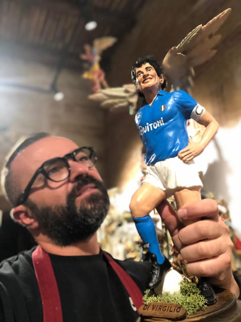 Il maestro Di Virgilio e la statuina di Maradona con le ali da angelo.