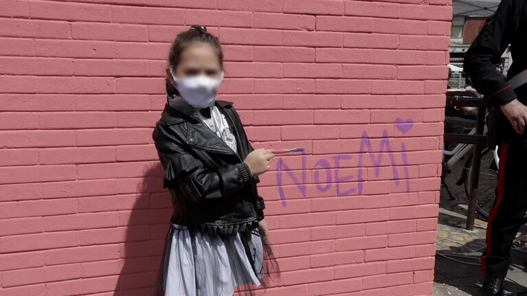 La piccola Noemi mentre firma il murale a lei dedicato.