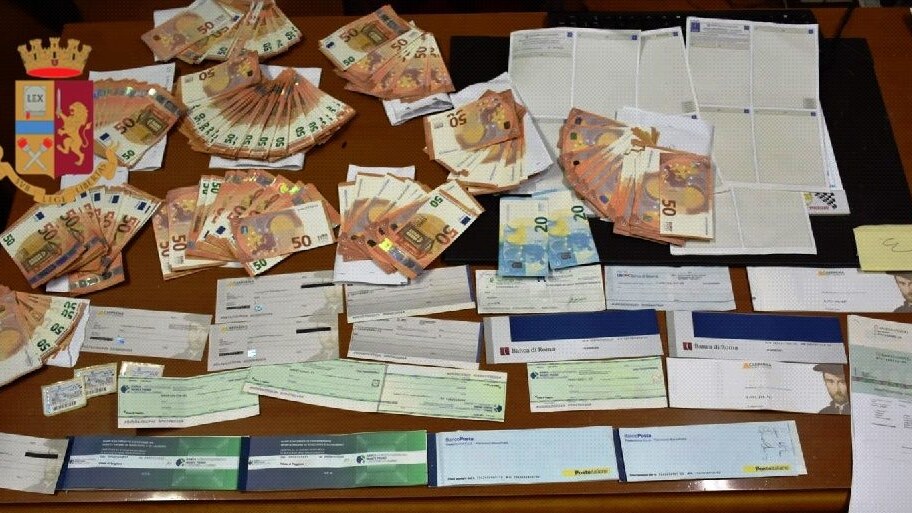 Il denaro e i libretti postali falsi sequestrati dalla polizia.