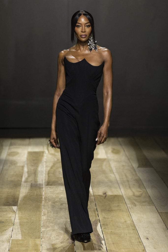 Naomi Campbell sfila per Alexander McQueen e una Venere in abito bustier con gioielli orchidea