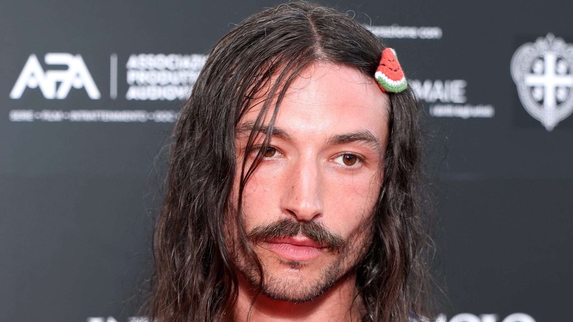 Il look di Ezra Miller in Sardegna: torna sul red carpet con la gonna e l’anguria tra i capelli