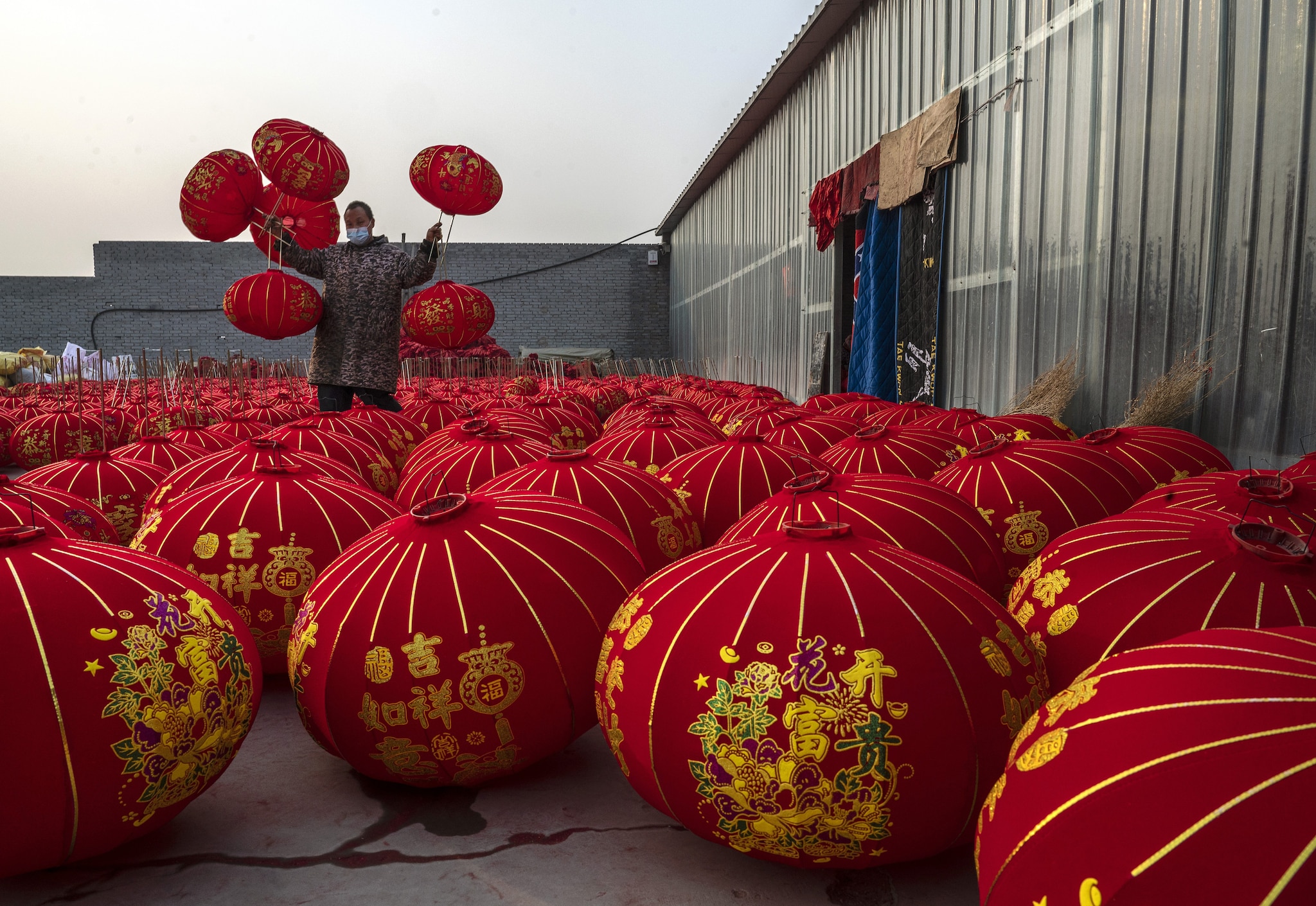 Un artigiano di Tuntou tiene tra le mani diverse lanterne rosse