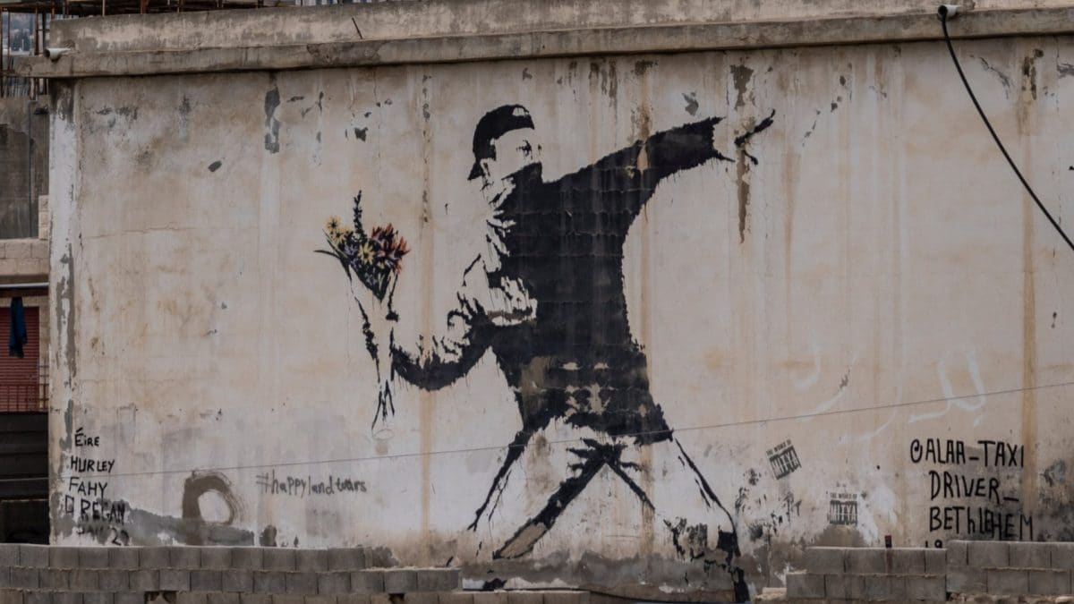 "Rage, Flower Thrower" di Banksy: manifestante con il volto coperto lancia un mazzo di fiori invece di una molotov