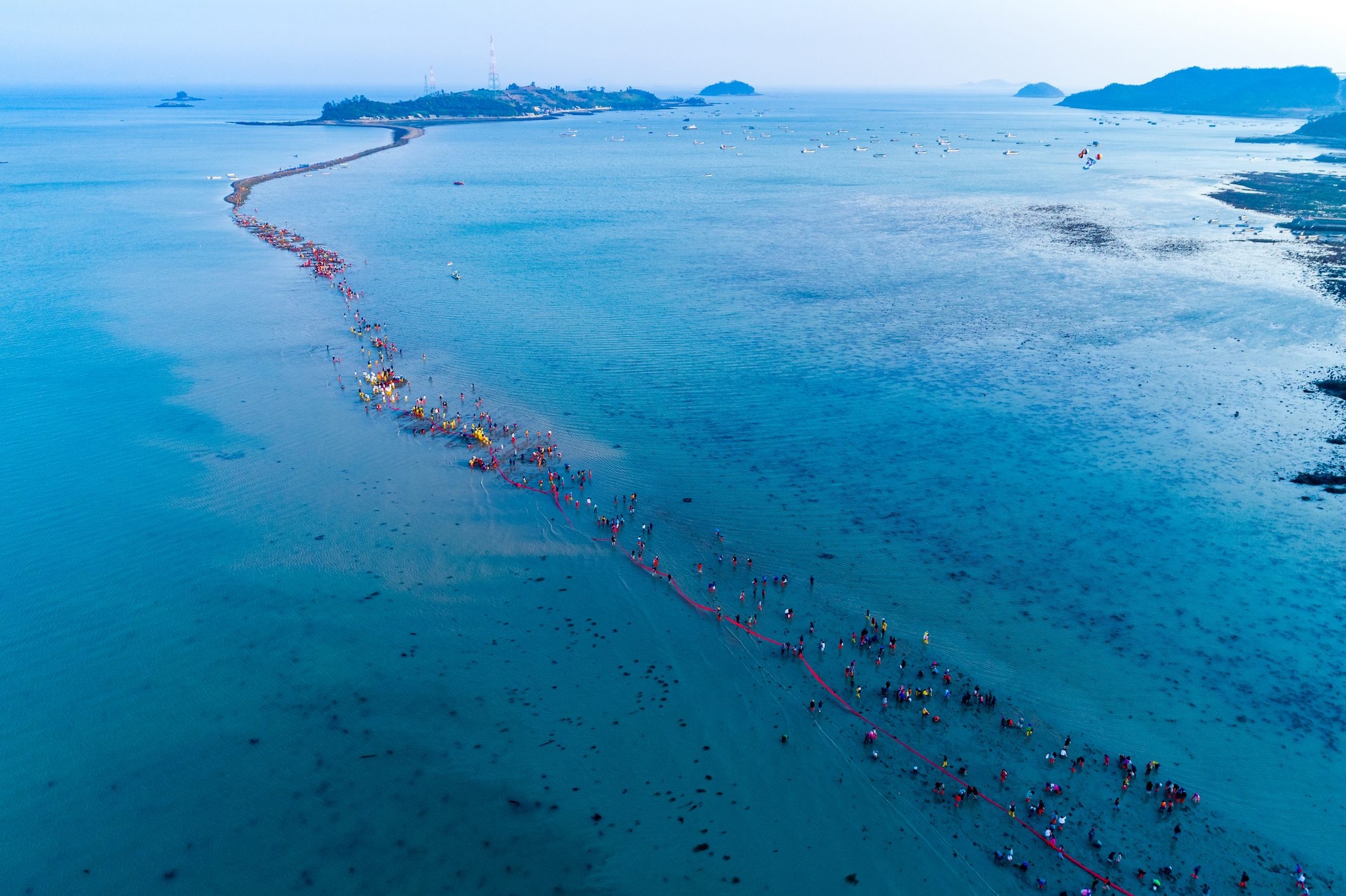 Turisti che attraversano la Sea Road rivelata dalla bassa marea