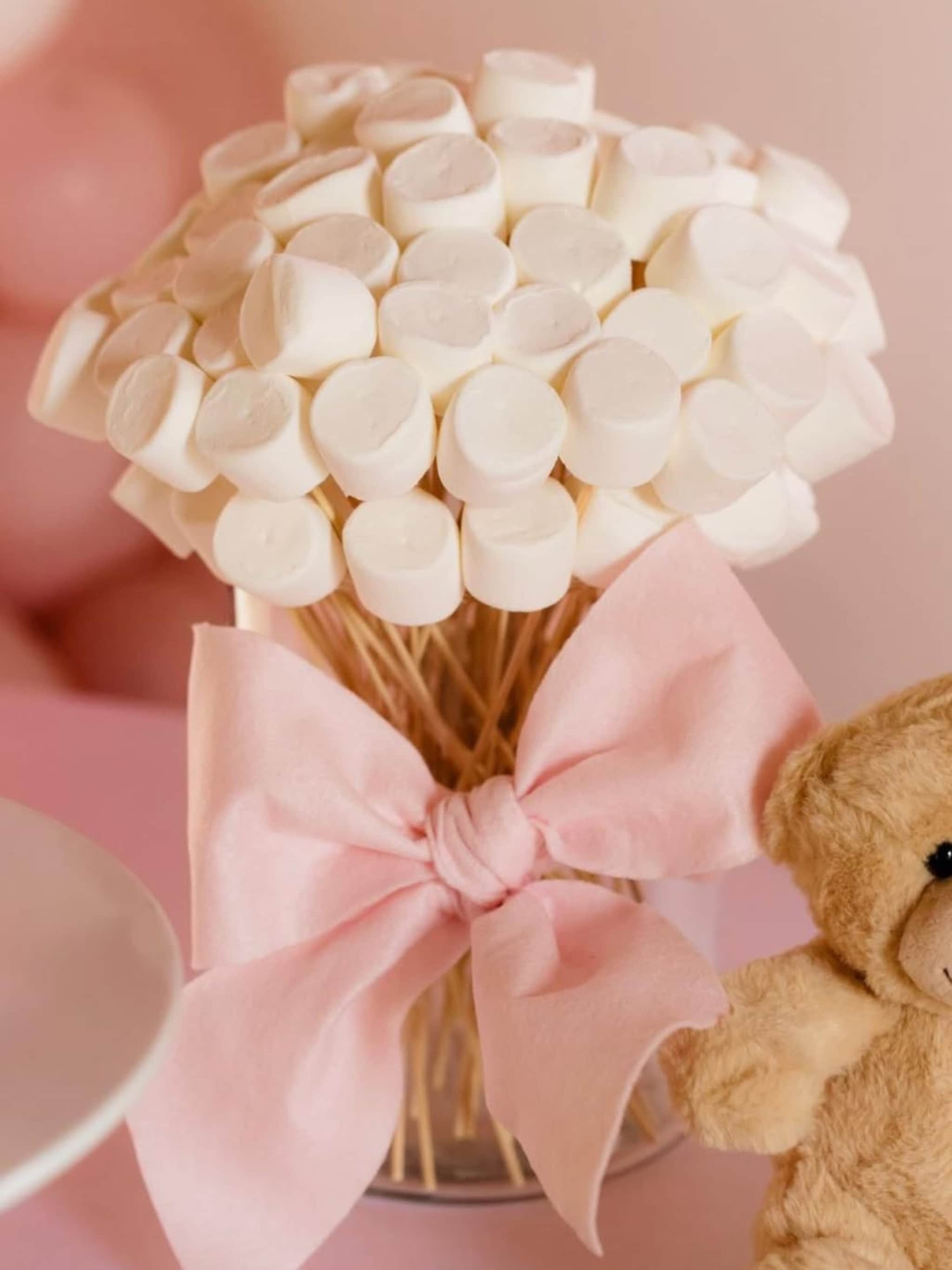 Un bouquet di marshmallow accompagnato da un fiocco rosa e un orsetto