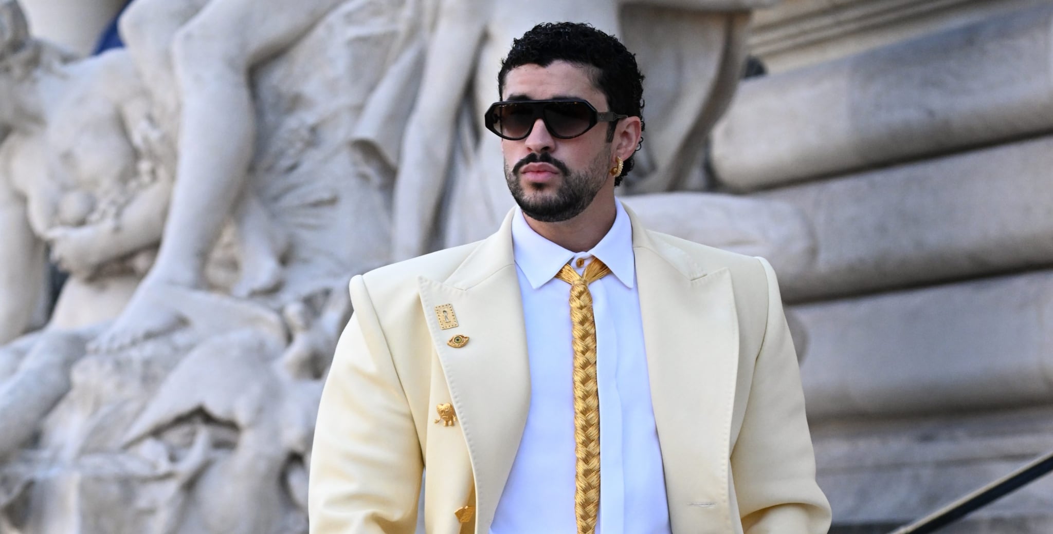 Bad Bunny con la cravatta-gioiello alla sfilata di Schiaparelli: ha una treccia di fili d'oro al collo