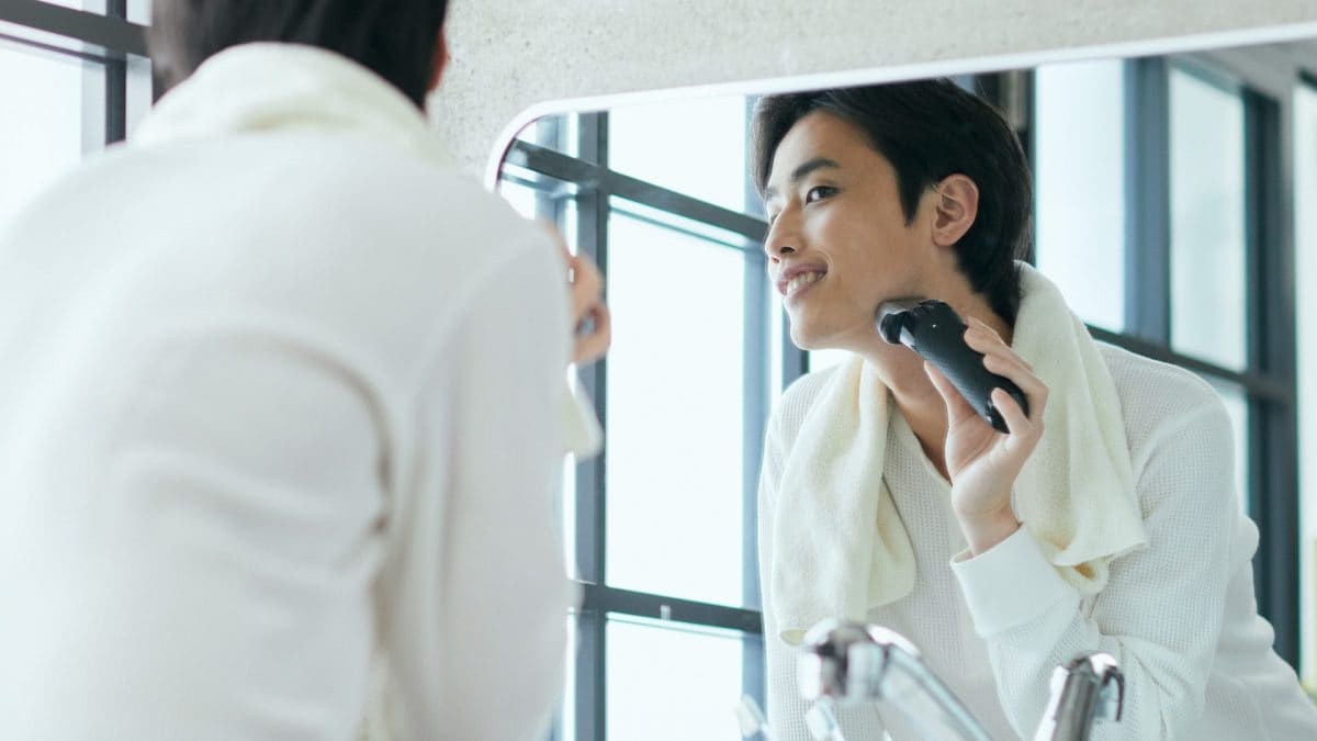 Un uomo si rade la barba con un rasoio elettrico