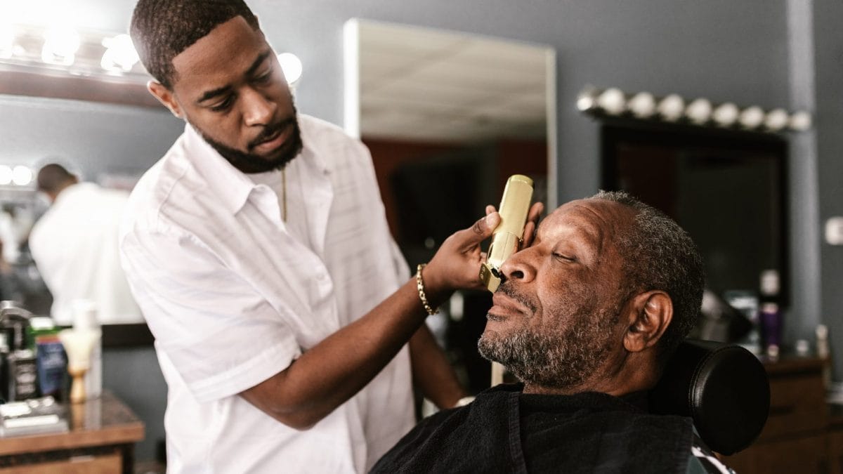 Un barbiere rade la barba di un uomo con un regolabarba