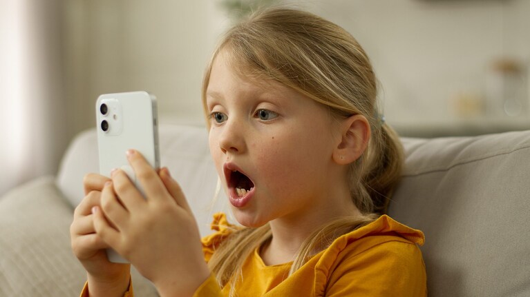 bimba guarda il cellulare spaventata